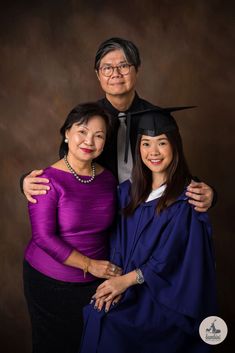 two women and a man are posing for a photo in their graduation gowns together