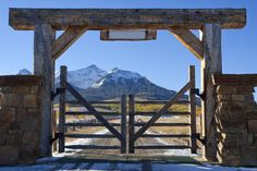 an old wooden gate with mountains in the background editorially framed by snow - capped peaks