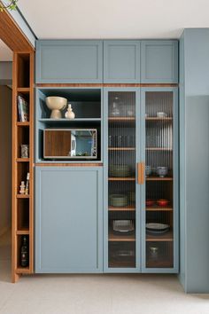 a kitchen with blue cupboards and glass doors on the front, and shelves in the back