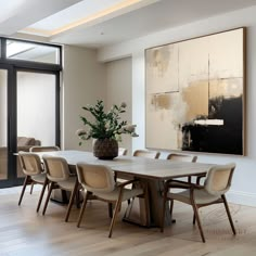 a dining room table with chairs and a large painting on the wall in front of it