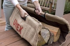 a woman holding a large bag over a firewood log on top of a wooden deck