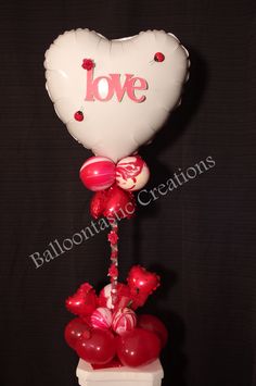 a balloon in the shape of a heart is attached to a stand with red and white balloons