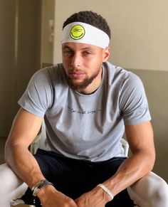 a man sitting on top of a bed wearing a white headband and looking at the camera