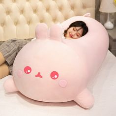 a woman laying in bed with a large pink stuffed animal on it's side