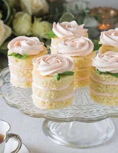 there are many small pieces of cake on the glass platter next to a cup and saucer