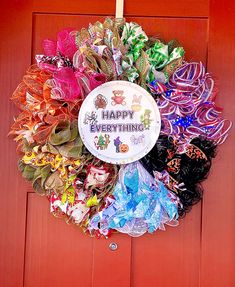 a happy everything wreath is hanging on the front door with ribbons and bows around it