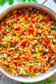 a pot filled with rice and vegetables on top of a table next to some parsley