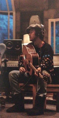 a man sitting on top of a wooden bench with a guitar in front of him