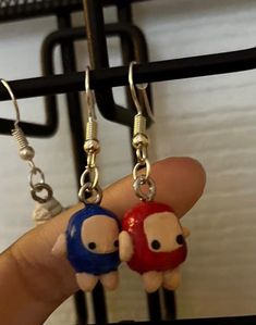 two little cartoon characters are hanging from earrings