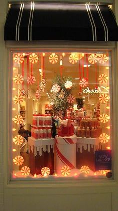 a store window with candy canes and candies in the display case, lit up by christmas lights