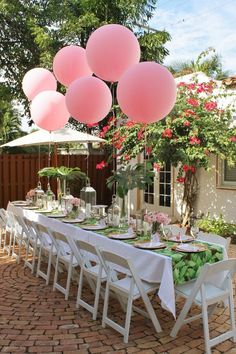 a table set up for a party with pink balloons