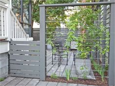 an outdoor dining area with chairs, table and planter on the side of the house