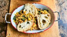 a bowl filled with bread and beans on top of a wooden table