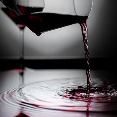 red wine being poured into a glass in the middle of a circular pattern with water droplets