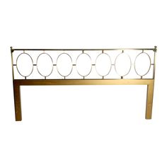 a gold metal headboard with circles on the top and bottom, against a white background