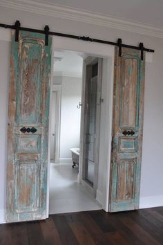 an open door leading to a bathroom with a tub in the background and wood flooring