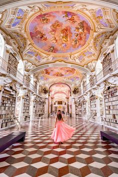 a woman in a pink dress is standing in the middle of a library