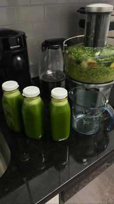 green smoothies are sitting on the counter next to juicers and blenders,