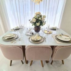 the table is set with plates, silverware and flowers in a vase on it