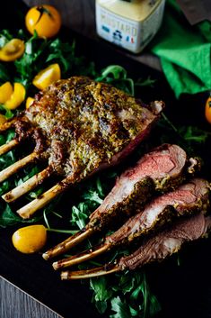 a large piece of meat on top of a bed of greens next to some oranges