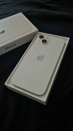 an apple phone in its box on a black surface with it's lid open