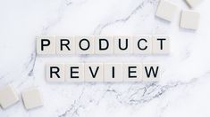 the word product review spelled with scrabble tiles on a white marble surface surrounded by cubes