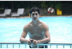 a man sitting on the edge of a swimming pool