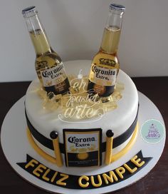 two bottles of corona beer on top of a cake with the words feliz cumple