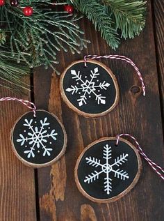 three snowflake ornaments are hanging on a wooden table