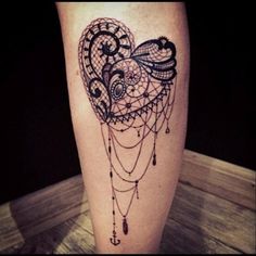 a tattoo on the leg of a woman with an intricate heart and chain attached to it