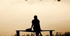 a person sitting on a bench with their feet up in the air and looking out into the distance