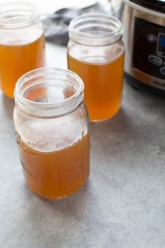 four jars filled with liquid sitting on top of a counter