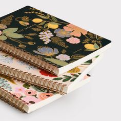 three notebooks are stacked on top of each other, with floral designs all over them