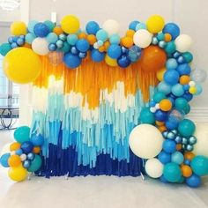 balloons and streamers are arranged in the shape of a rainbow - colored arch for a birthday party