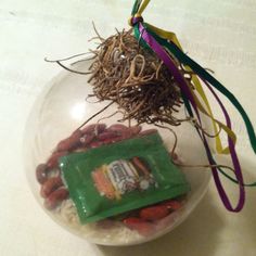 a glass ball ornament filled with food and ribbons on top of a table