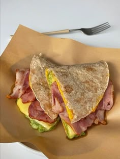 a sandwich with ham, cheese and lettuce on it next to a fork