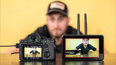 a man sitting in front of a camera next to a small device with an image on it