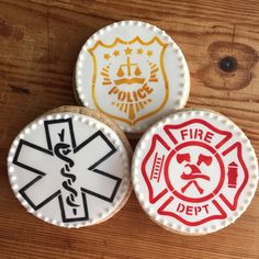 three cookies decorated like fire department emblems on top of a wooden table next to each other