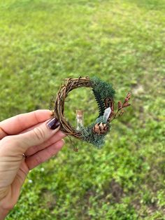 a hand holding a tiny wreath made out of twigs