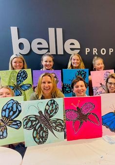 a group of people holding up paintings with butterflies on them and the words bellie prop