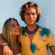 a young man and woman are posing for a photo in front of a white wall