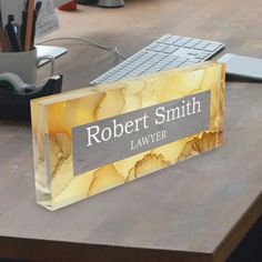 a glass business card sitting on top of a wooden desk next to a computer keyboard