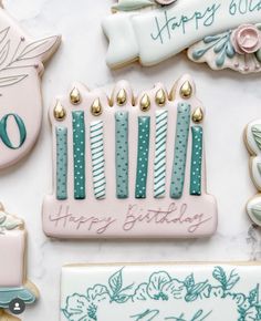 decorated birthday cookies with candles and flowers on a white counter top, next to cookie cutters that say happy birthday