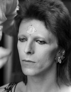 a woman getting her make - up done in black and white with flowers on her forehead