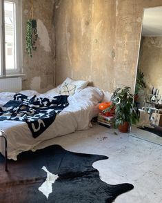 a bed sitting in a bedroom next to a mirror and potted plant on the floor