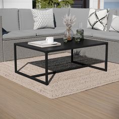 a black coffee table sitting on top of a wooden floor next to a gray couch