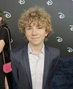 a young man with curly hair wearing a suit