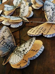 some paper butterflies with writing on them sitting on top of a wooden table next to each other