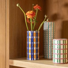 three vases with flowers in them sitting on a shelf next to each other,