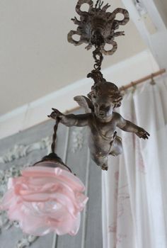 a chandelier hanging from the ceiling with an angel figurine on it